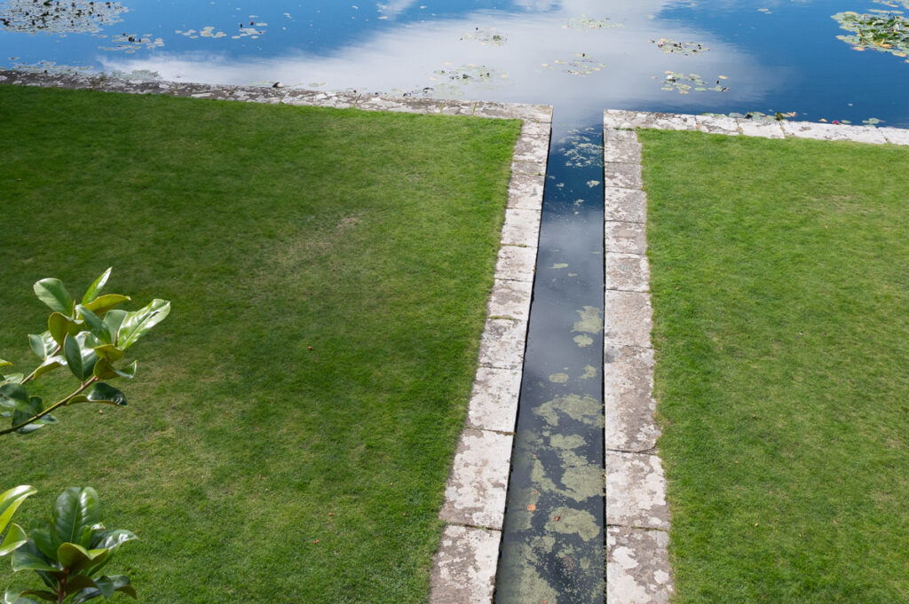 lawn with water rill and pond reflecting clouds